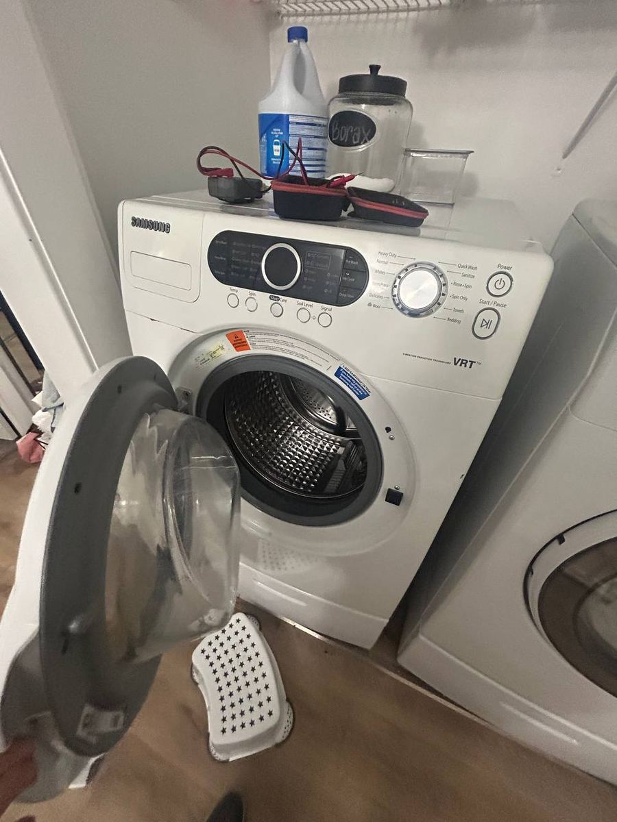 Front-load washer opened for diagnosis in a laundry closet